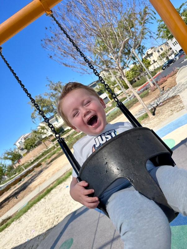  young boy laughing on a swing